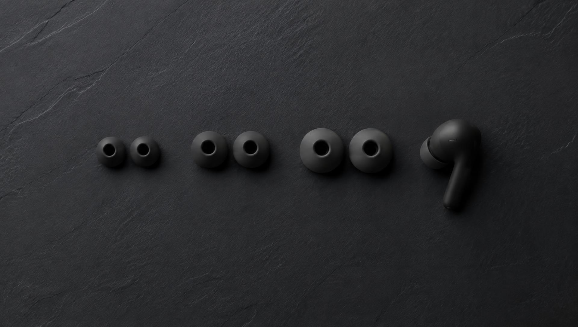 Three sizes of silicone ear tips laid out beside an earbud